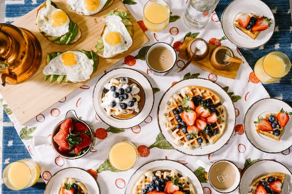 top view of a breakfast table with waffles, eggs and fruit